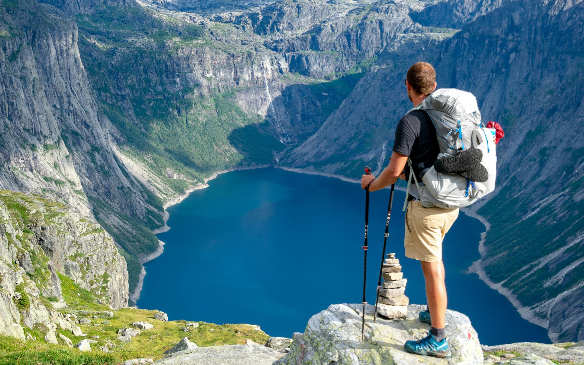 Wanderer blickt von einem Felsen über einen Fjord in Norwegen