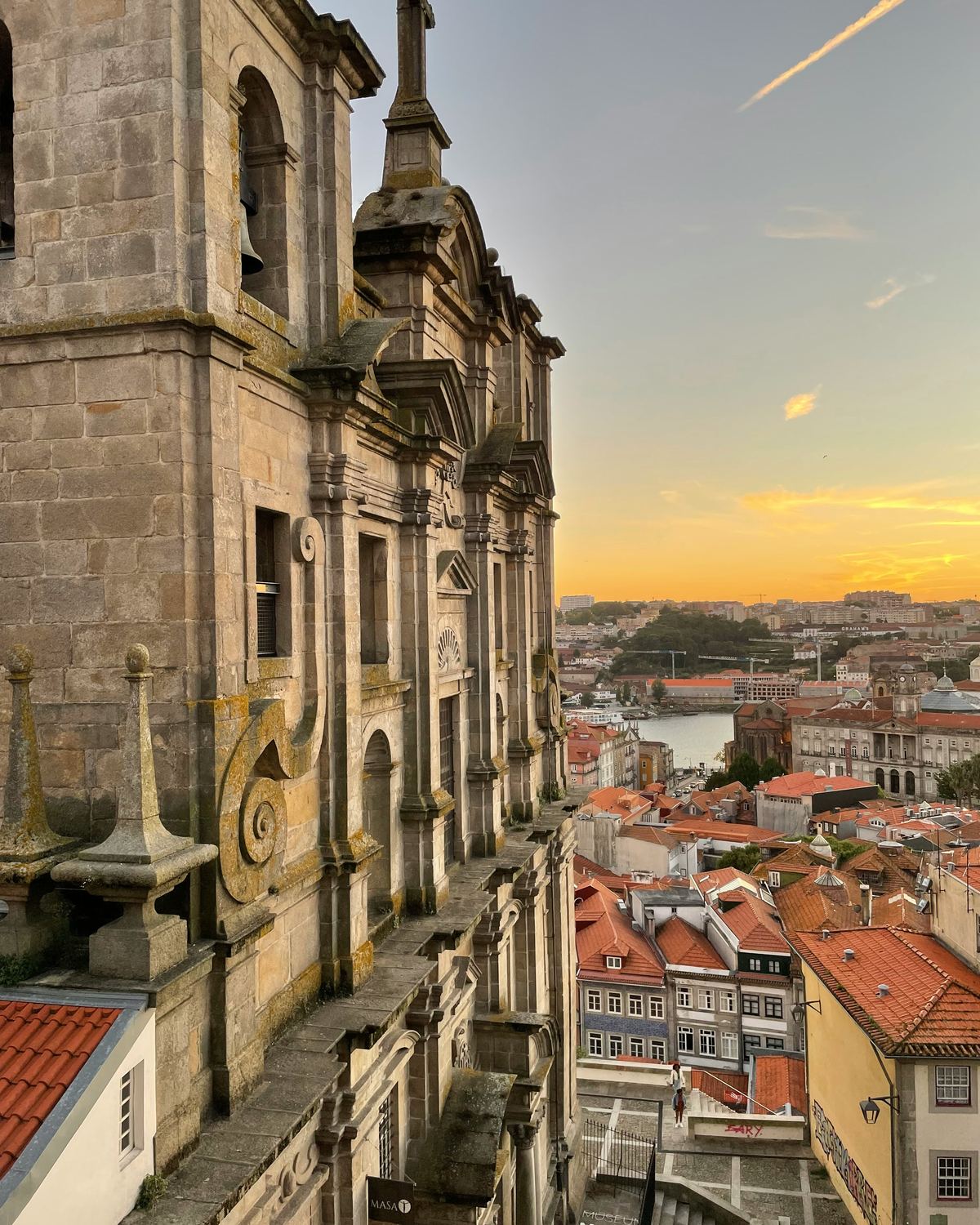 Barocke Kirchenfassade über den roten Dächern von Porto im Abendlicht