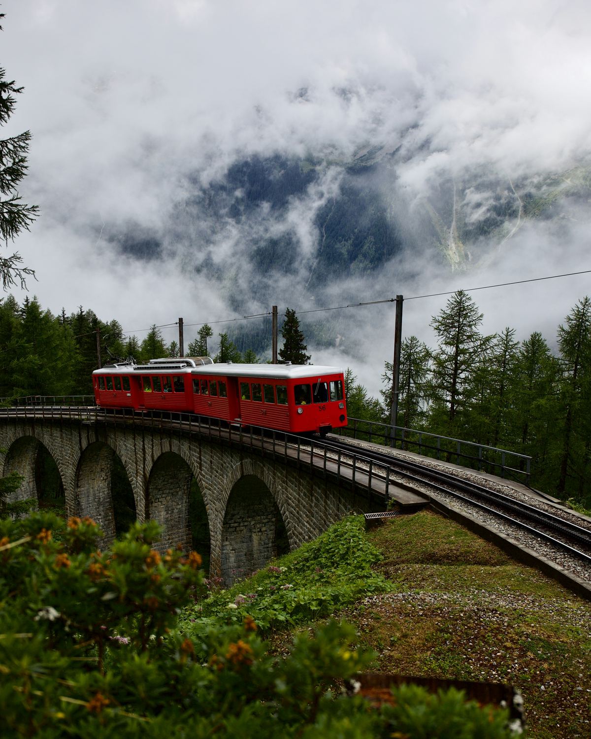 Rote Bergbahn auf einem Steinviadukt in den Alpen